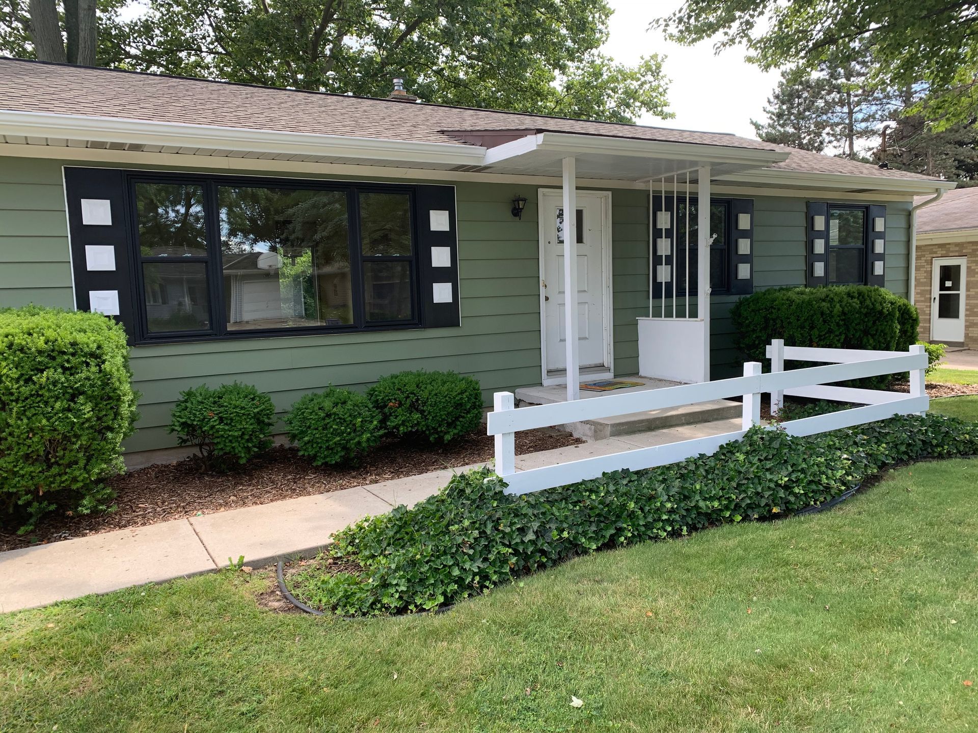 A green house with a white fence in front of it