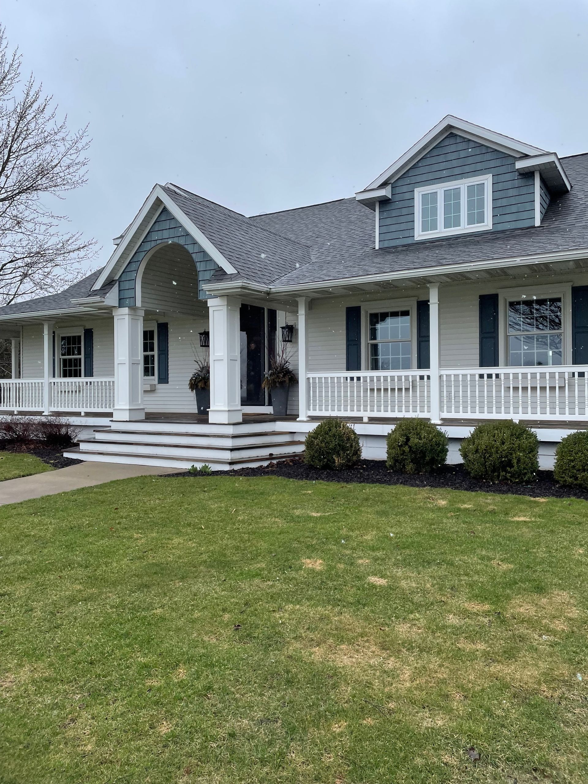 A large white house with a large porch and a gray roof.
