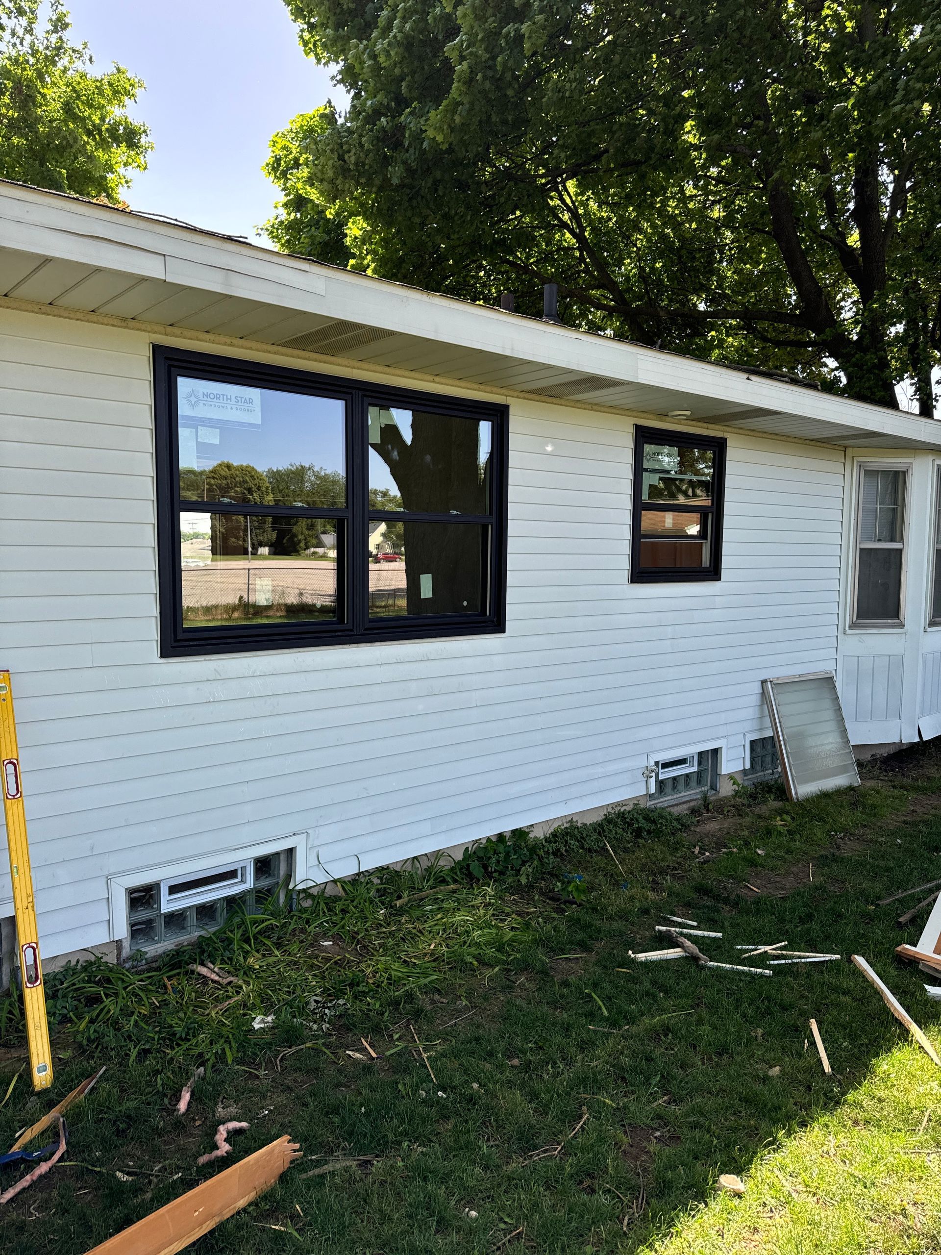 A white house with black windows is sitting on top of a grassy hill.