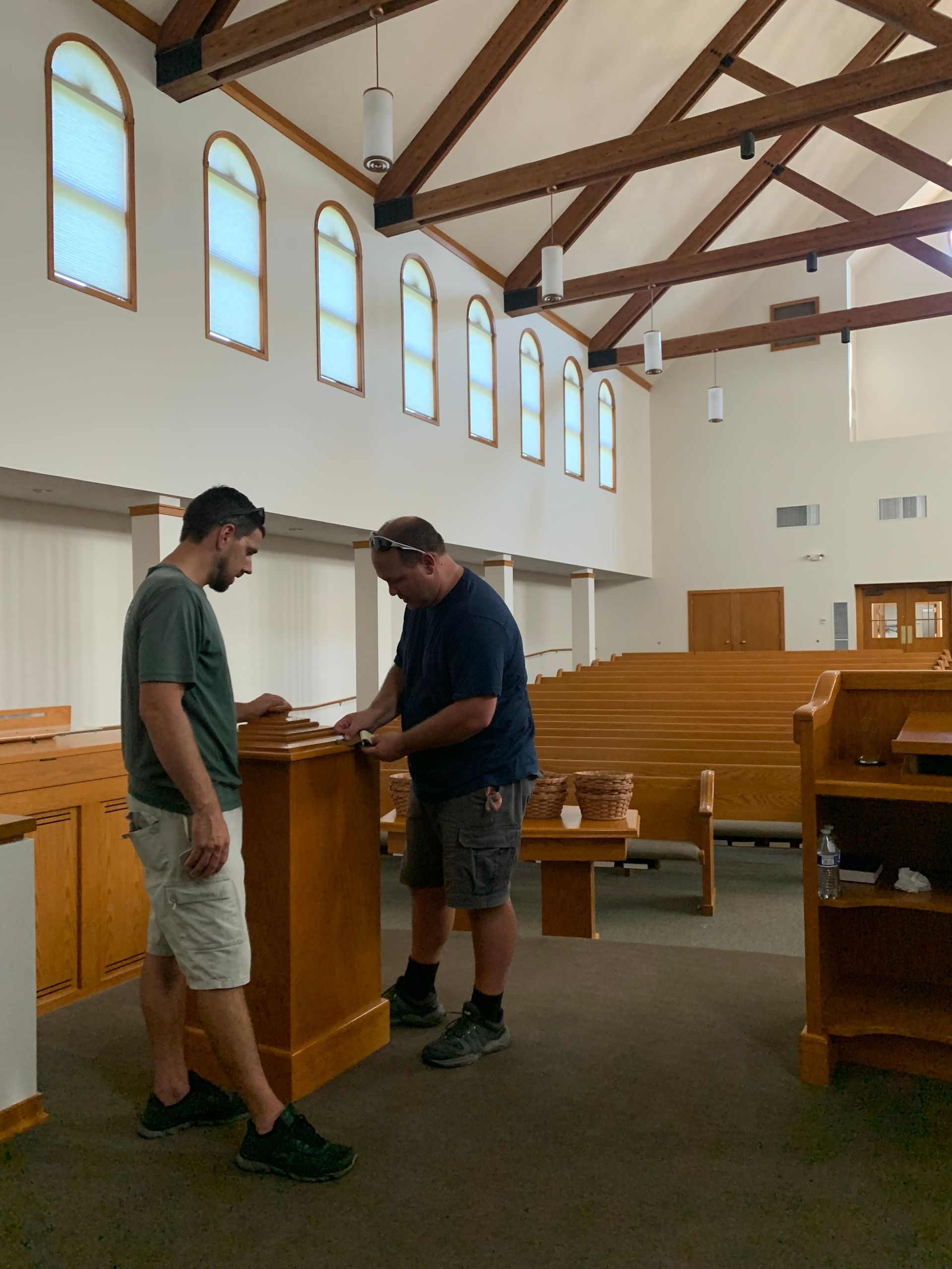 Two men are working on a wooden podium in a church