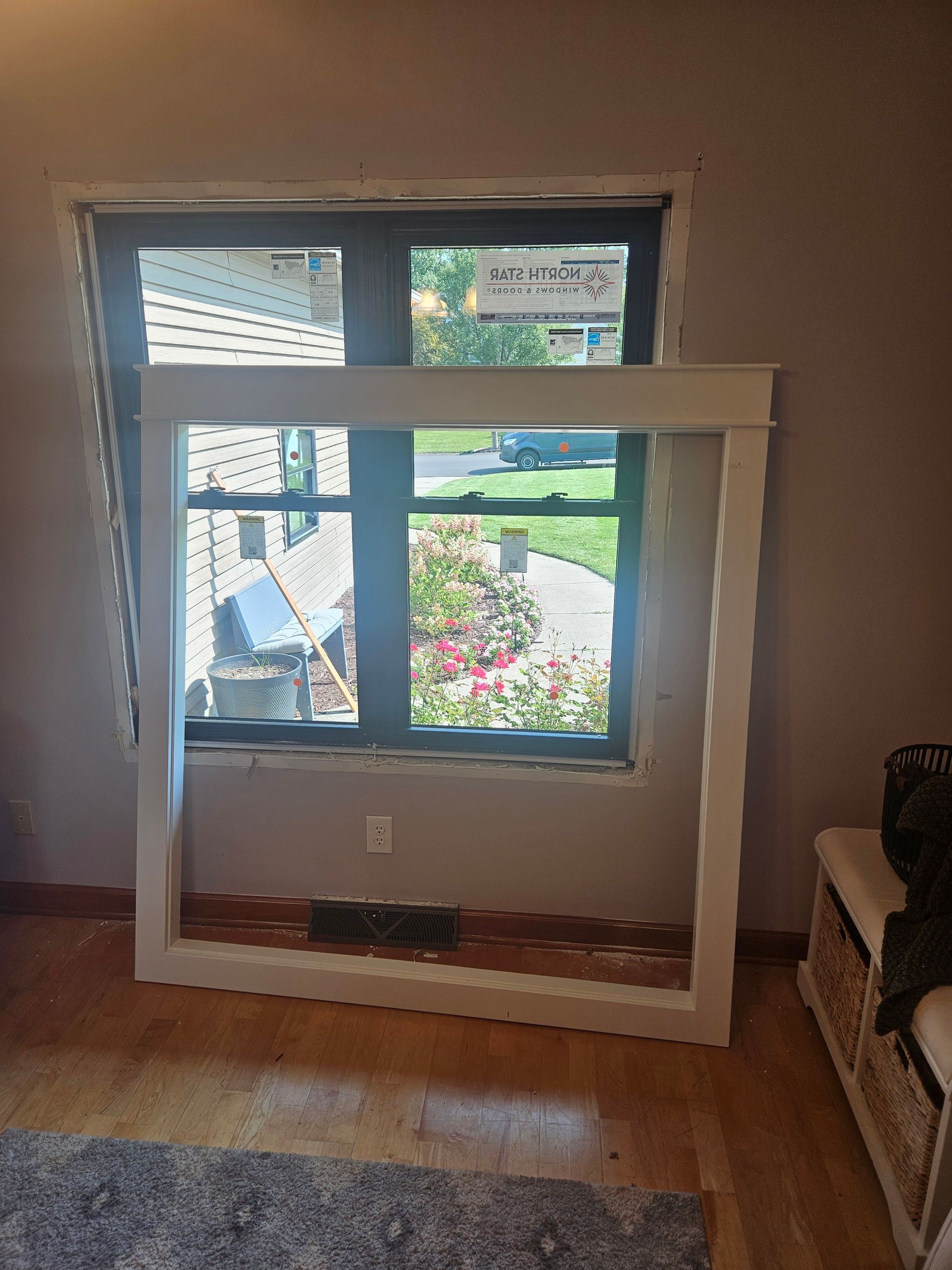 A large white frame is sitting in front of a window in a living room.