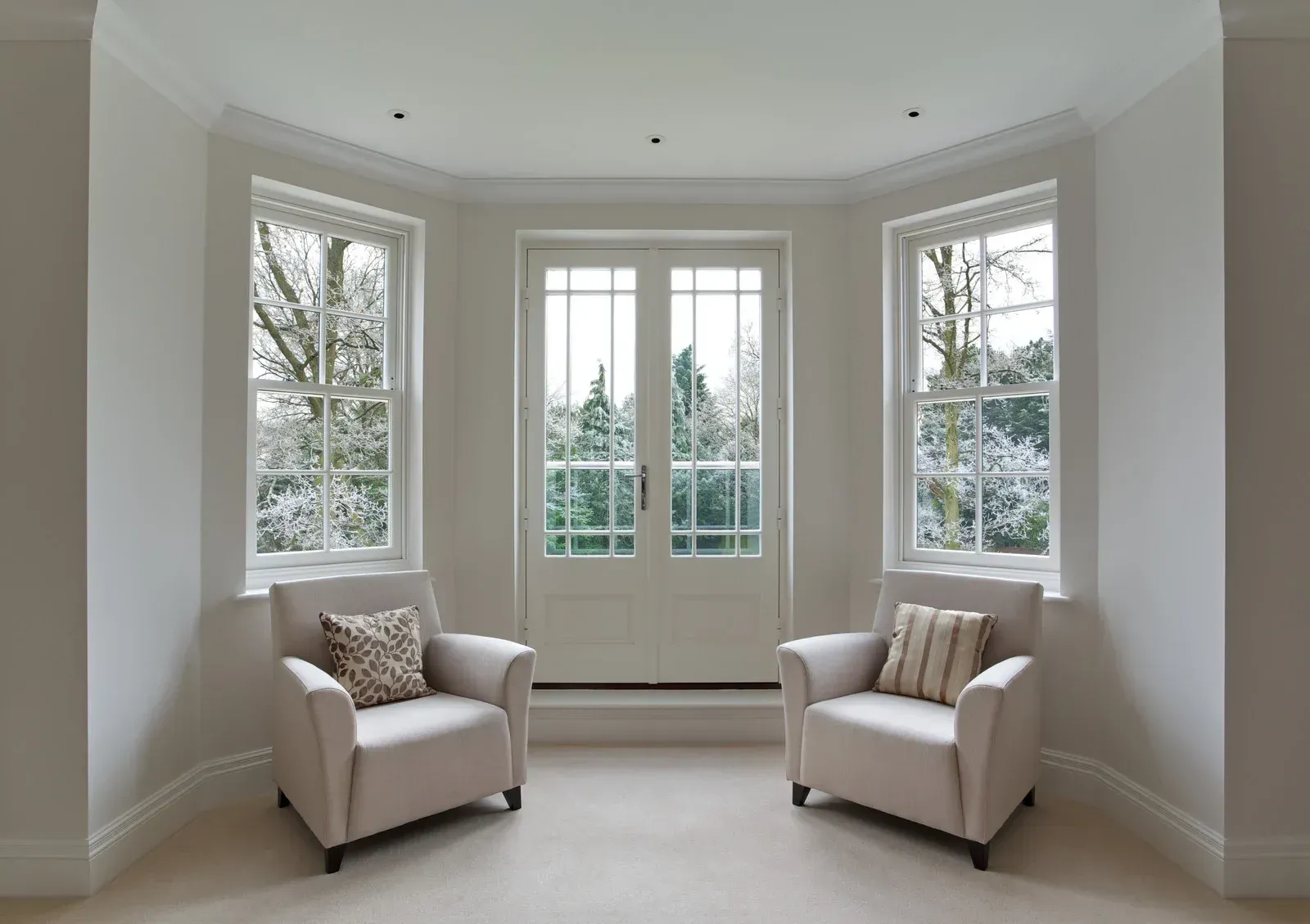 A living room with two chairs and two windows