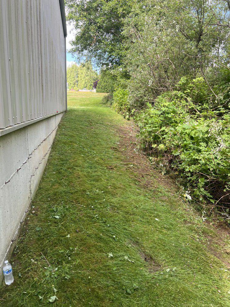A bottle of water is sitting in the grass next to a building.