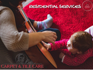 A woman is reading a book to a baby on a red rug.