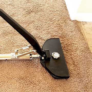 A vacuum cleaner is sitting on top of a brown carpet.