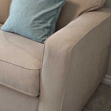 A beige couch with a blue pillow on it in a living room.