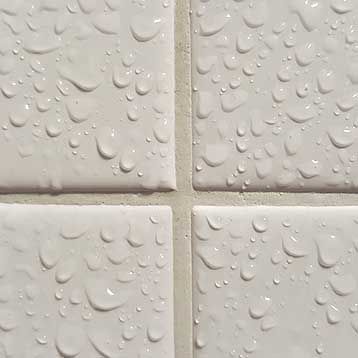 A close up of a tile with water drops on it.