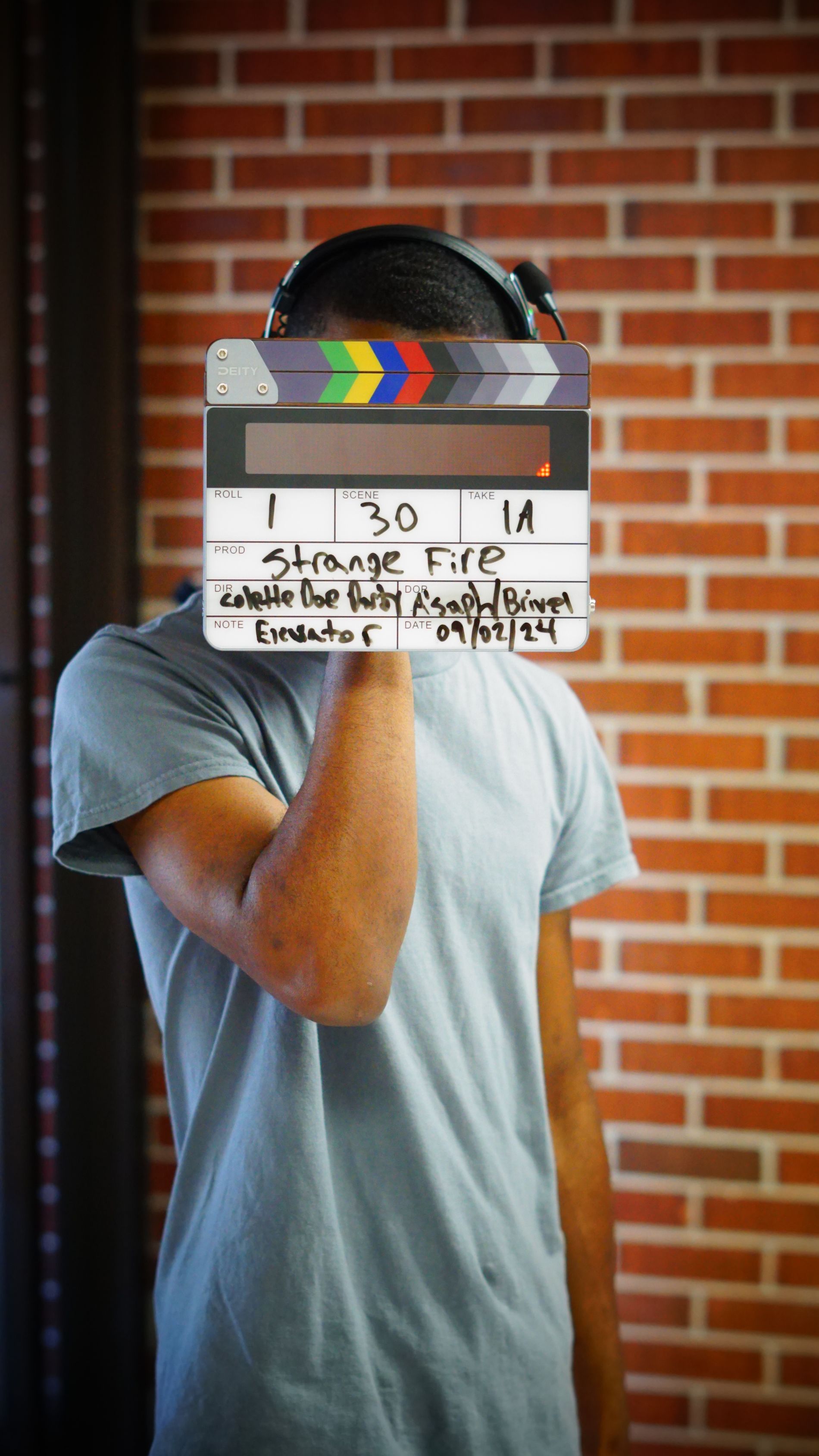 A man is holding a clapper board in front of his face.