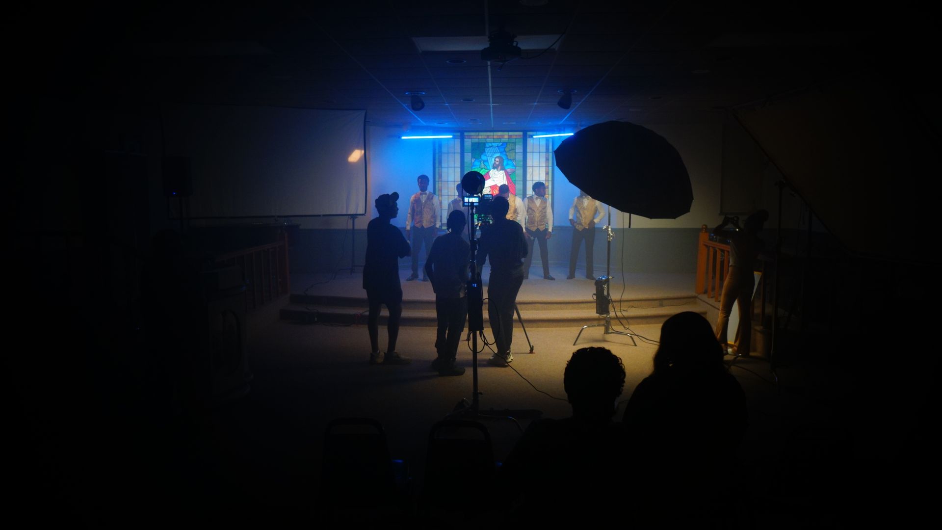 A group of people are standing on a stage in a dark room.