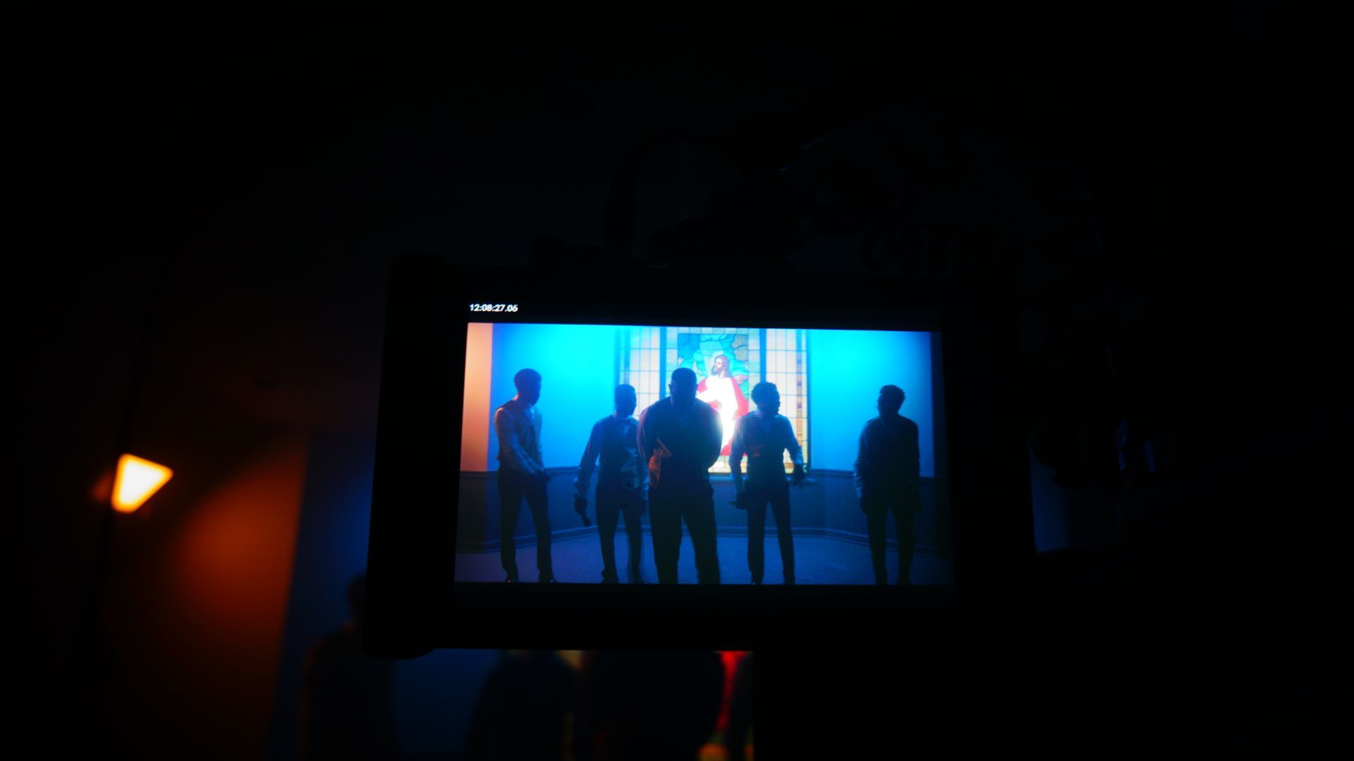 A group of people are standing in front of a window on a television screen.