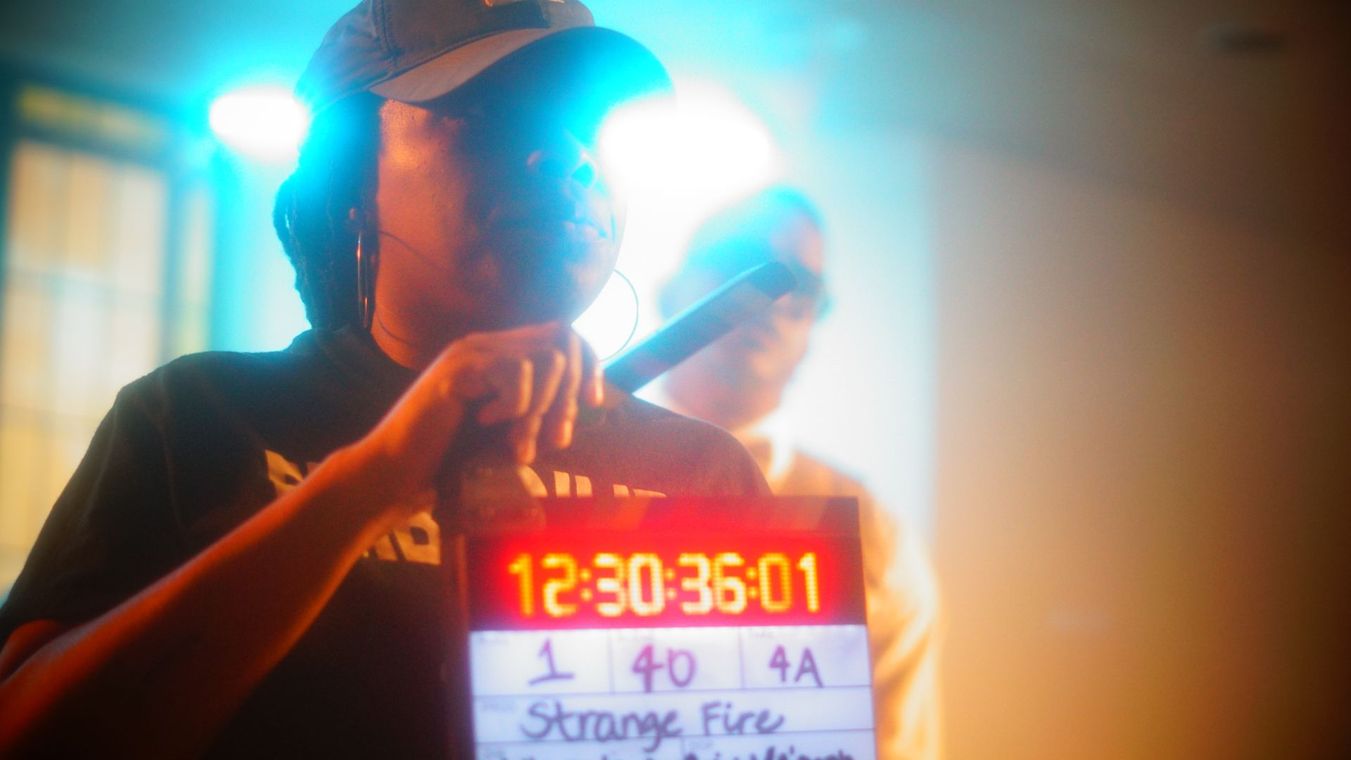 A man is holding a clapper board with a timer on it.