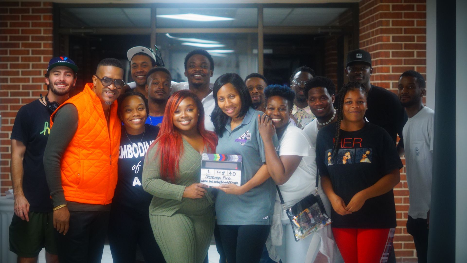 A group of people are posing for a picture in front of a brick building.
