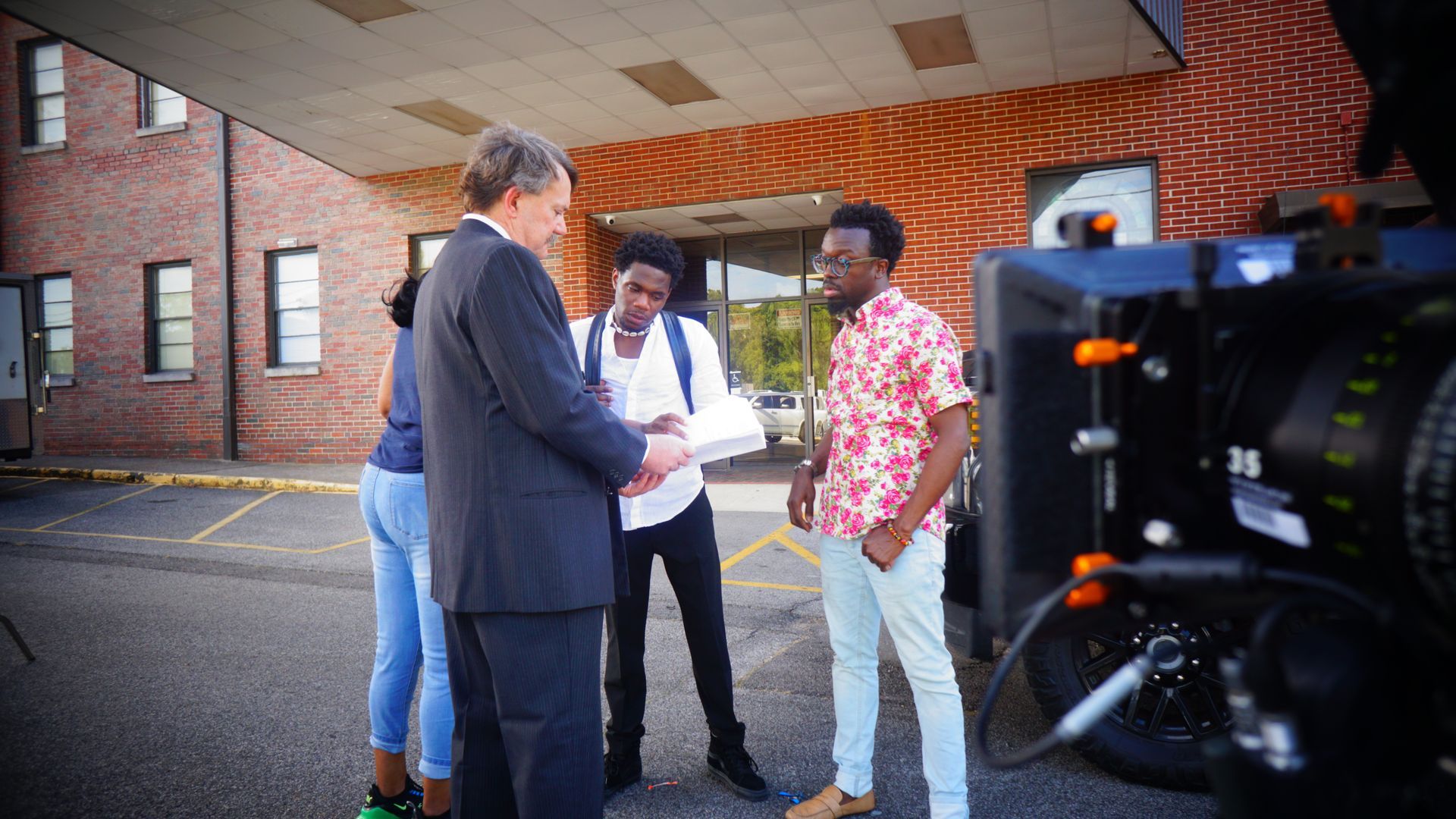 A group of people are standing in front of a building talking to each other.