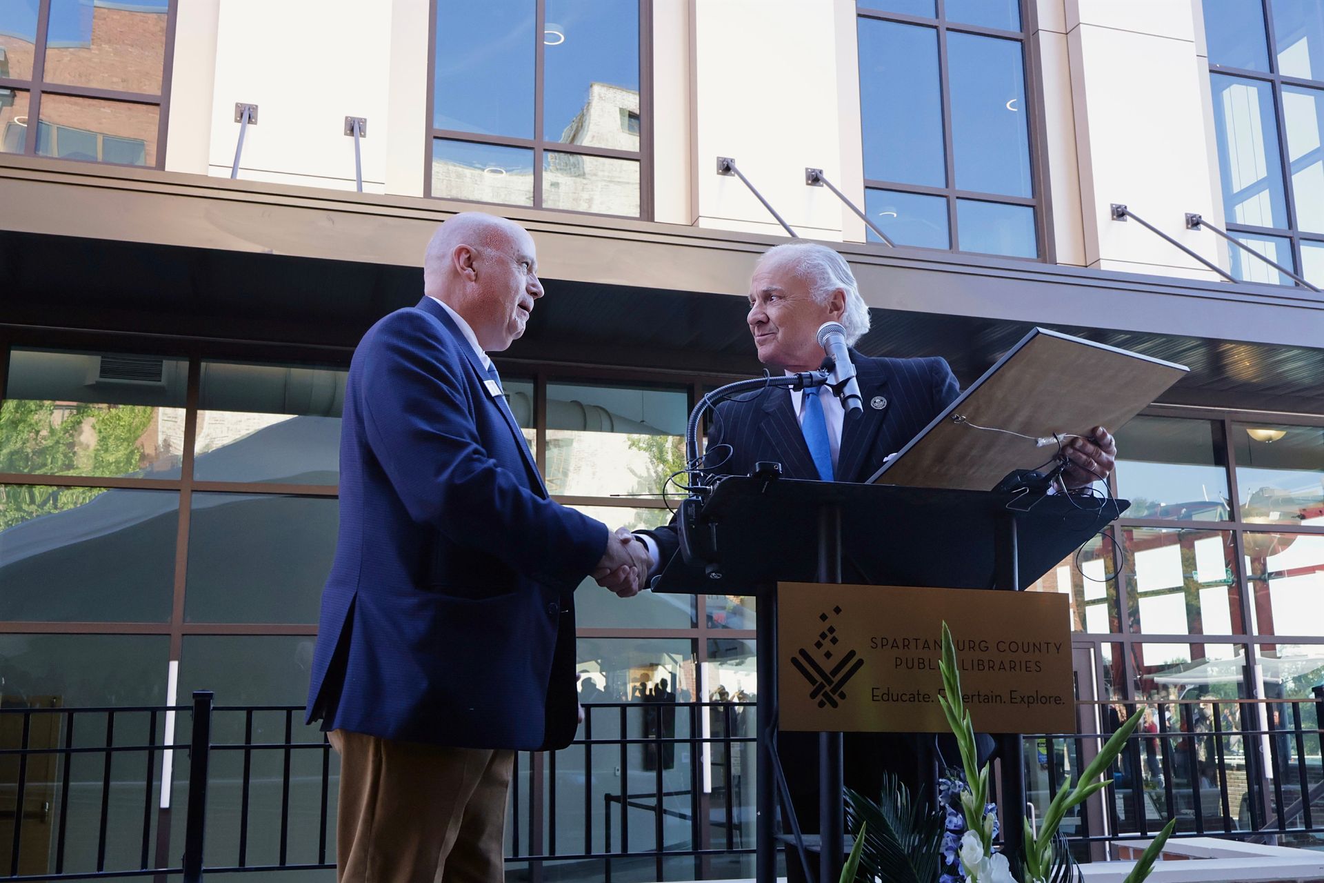 A woman with curly hair is smiling in front of a blue background.