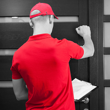 A person in a red shirt and cap knocking on a black door, holding a clipboard.