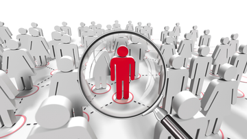 Magnifying glass focuses on a red figure in a crowd of white figures, illustrating focus.