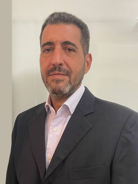 Um homem com barba está vestindo um terno e uma camisa rosa.
