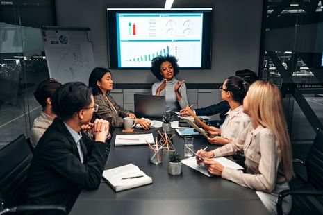 Um grupo de pessoas está sentado ao redor de uma mesa tendo uma reunião.