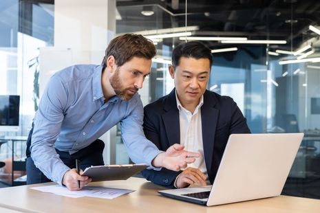 Dois homens estão olhando juntos para um laptop.