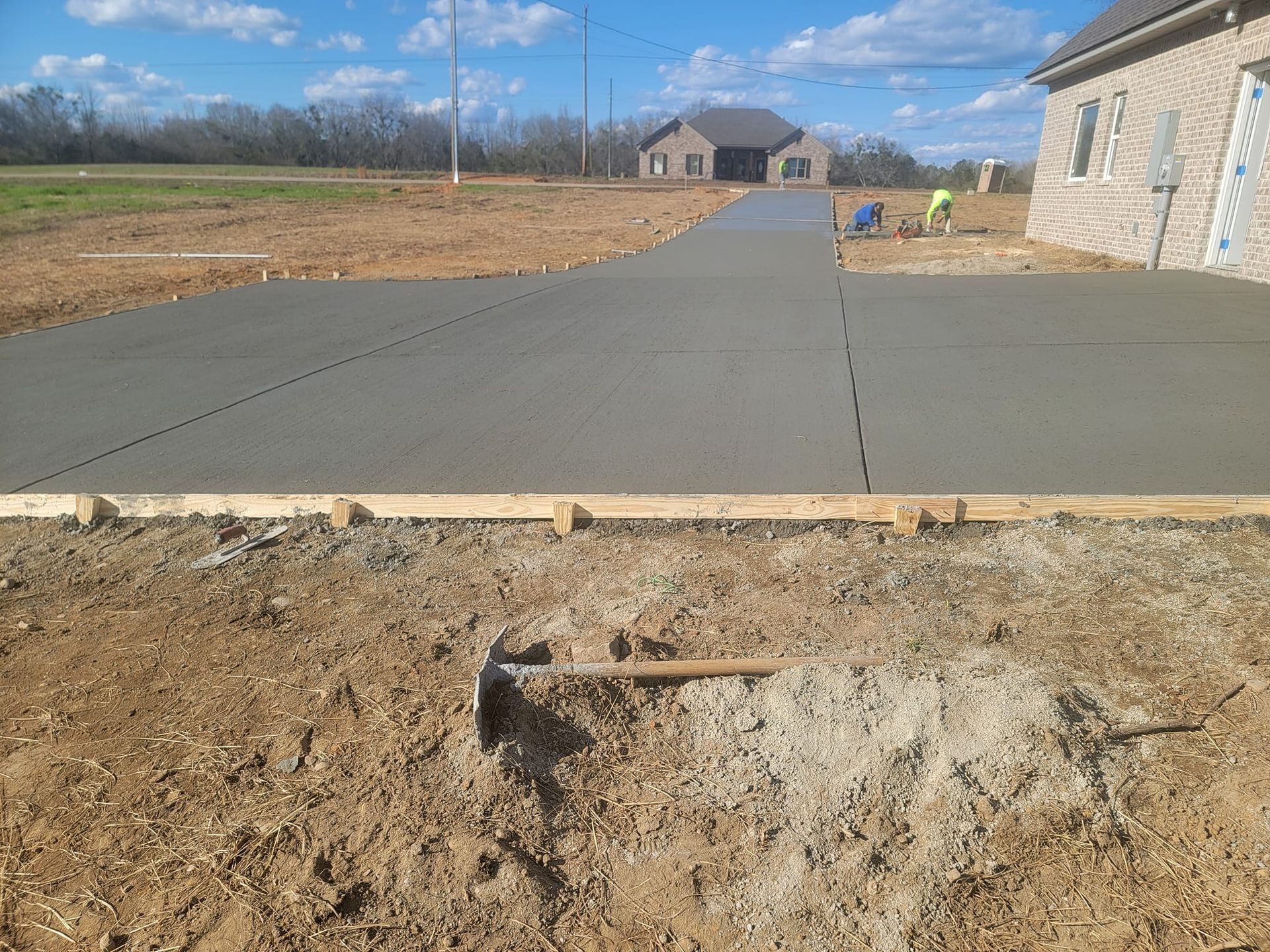 Newly poured concrete driveway with wooden forms, house in background.