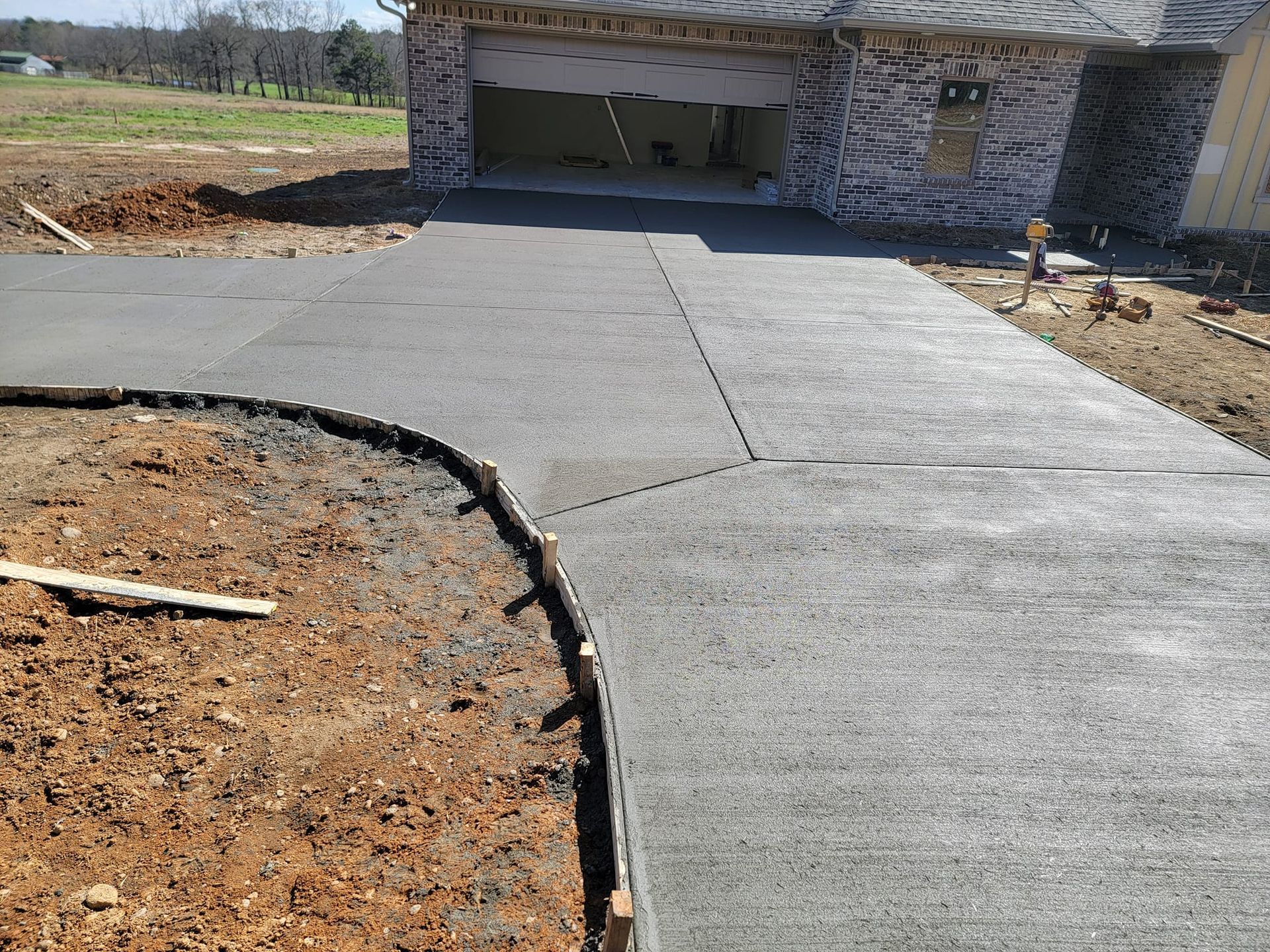 Newly poured concrete driveway leading to a garage under construction.