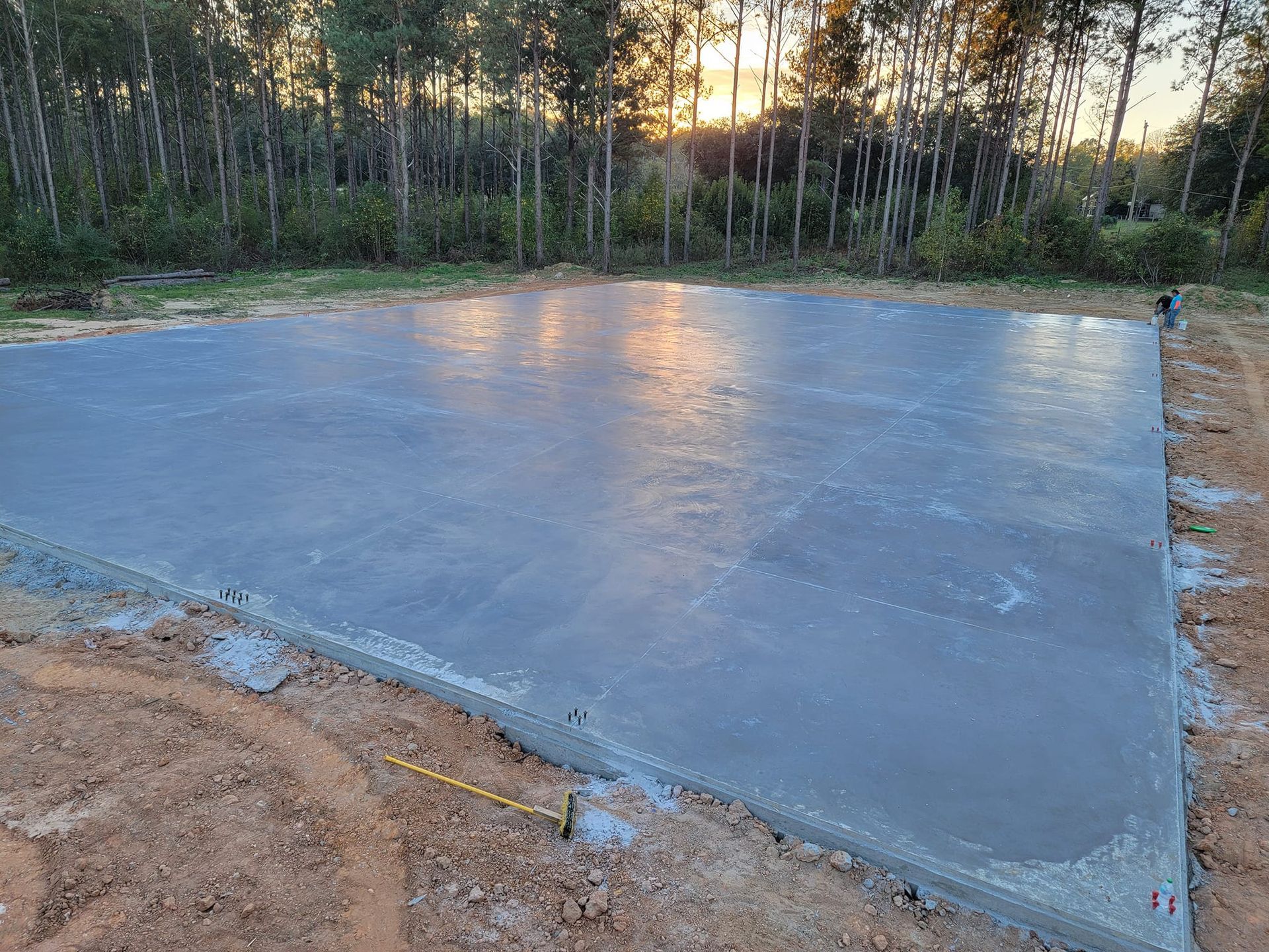 Freshly poured concrete slab in an outdoor setting, reflecting sunlight.