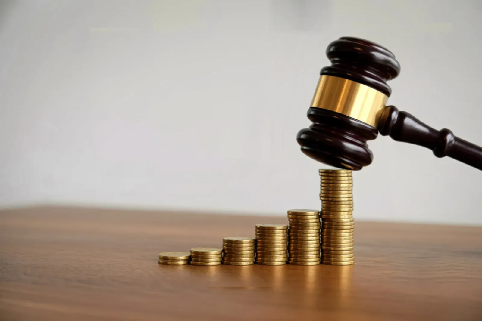 Gavel hitting a stack of coins arranged like a bar graph, implying financial decisions or judgments.