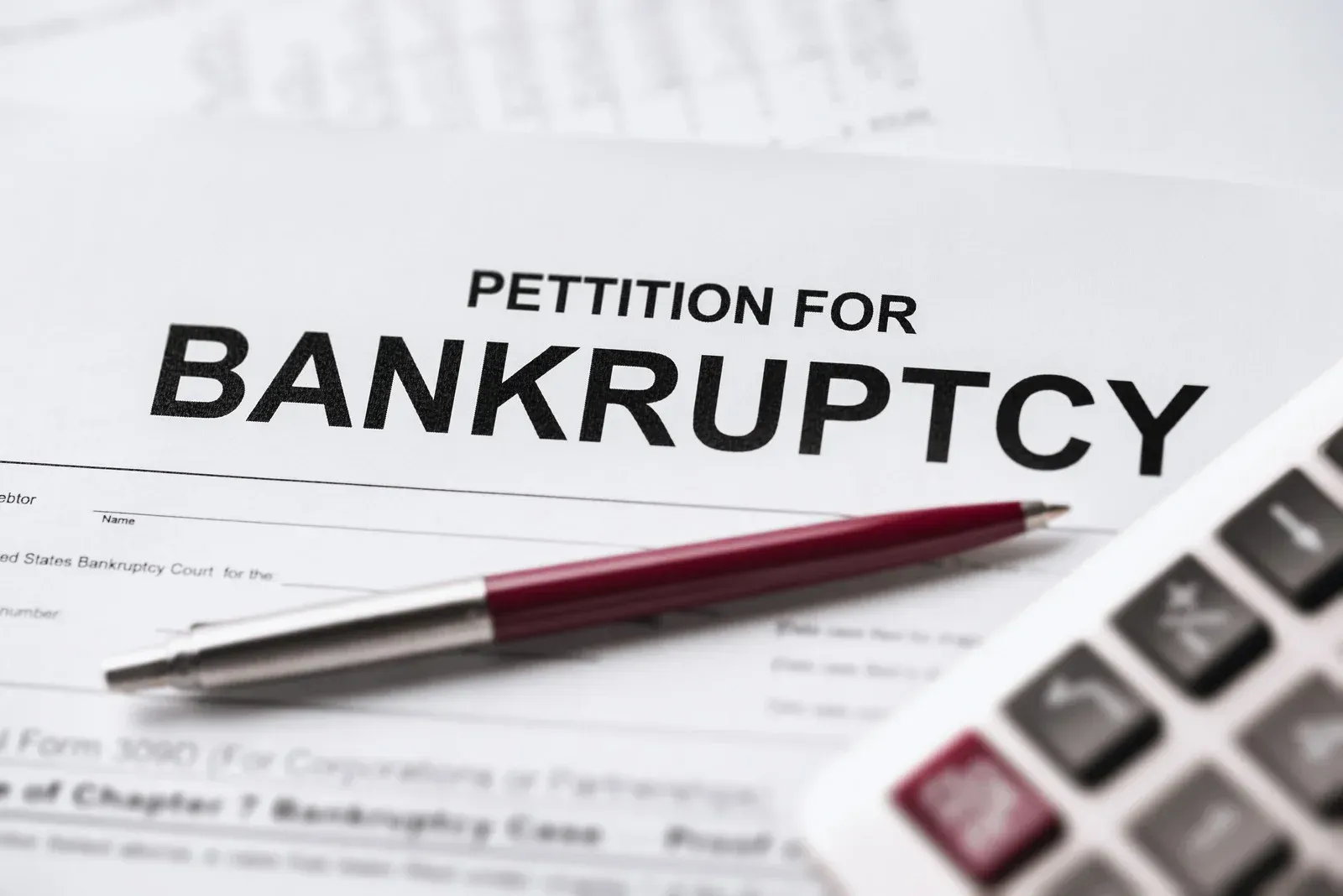 Petition for Bankruptcy document with a pen and calculator.