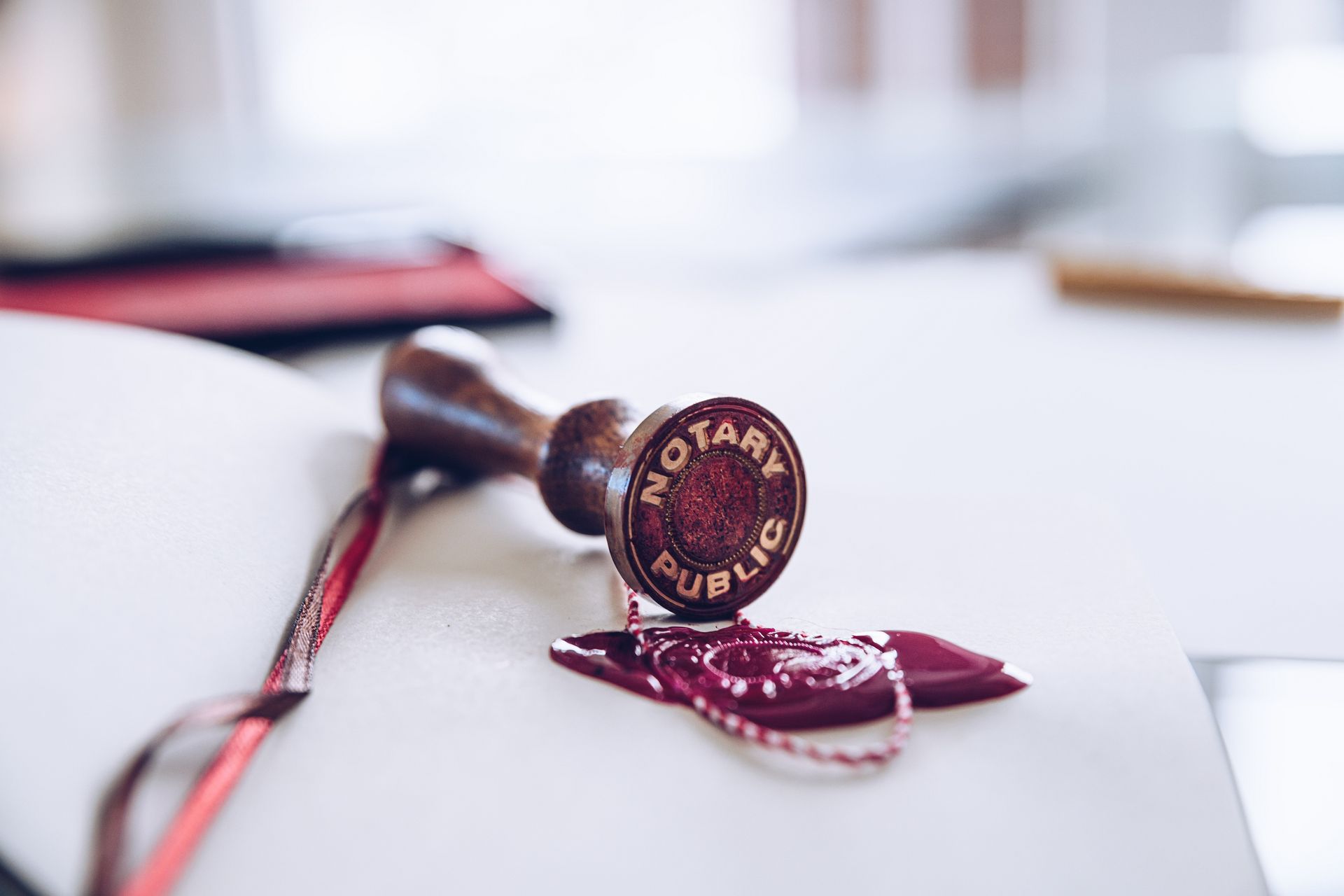 Notary public stamp on an open book, next to a burgundy seal and ribbon.
