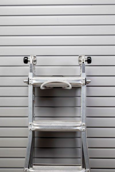 A ladder is leaning against a white wall.