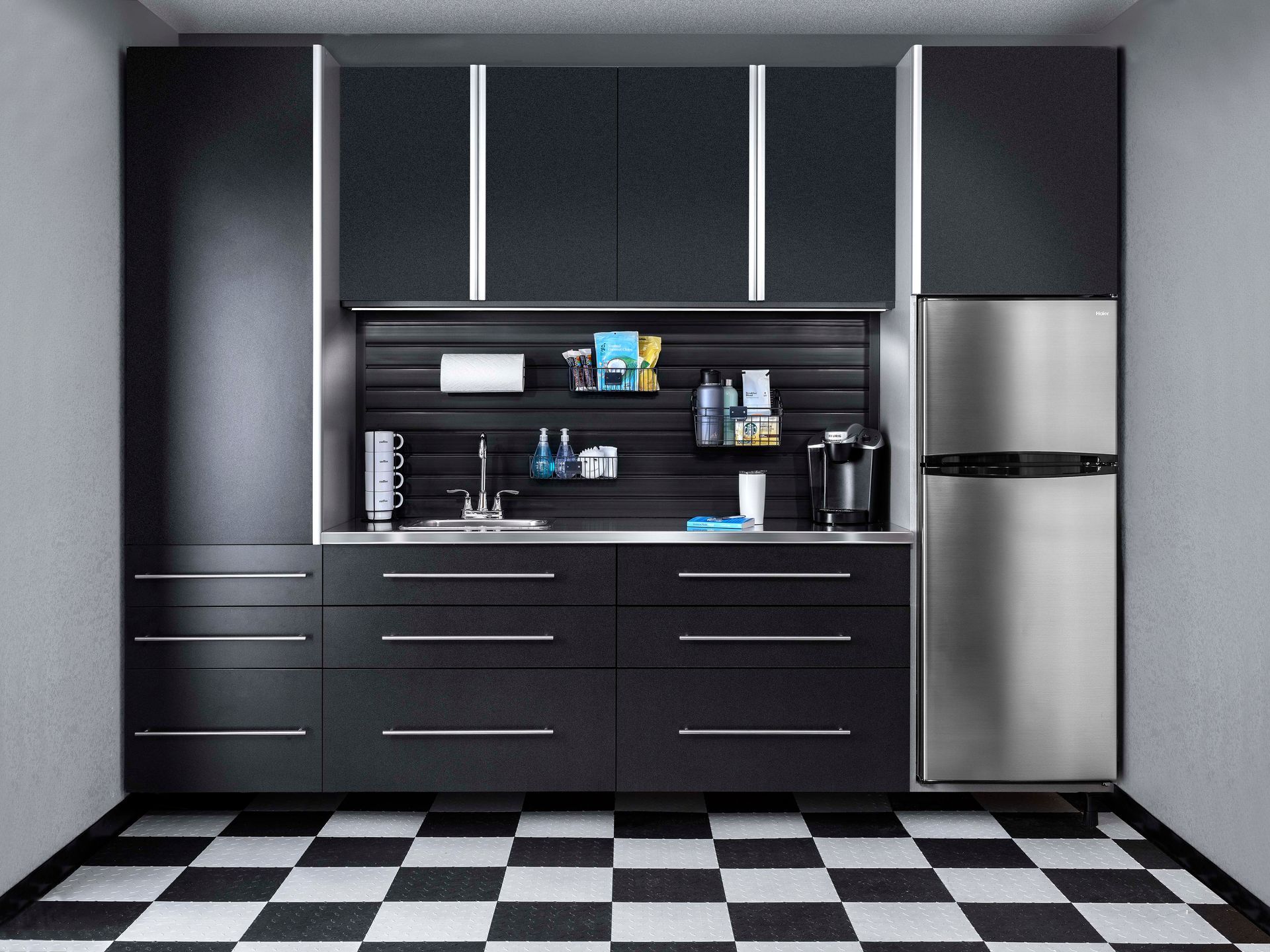 Black garage storage system with a sink, refrigerator, and black and white checkered floor.