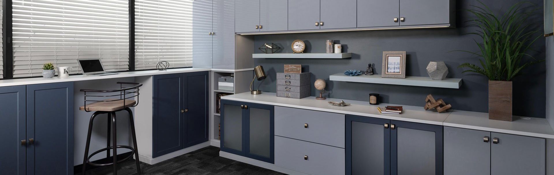 A Home Office  with a lot of cabinets and shelves and a desk with a laptop on it.