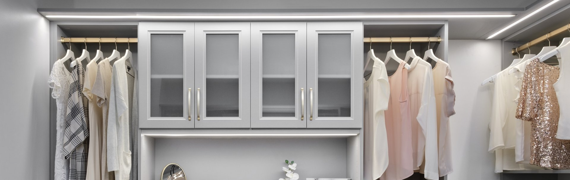 A well-organized walk-in closet with dark-colored drawers and shelves, filled with clothes and shoes.