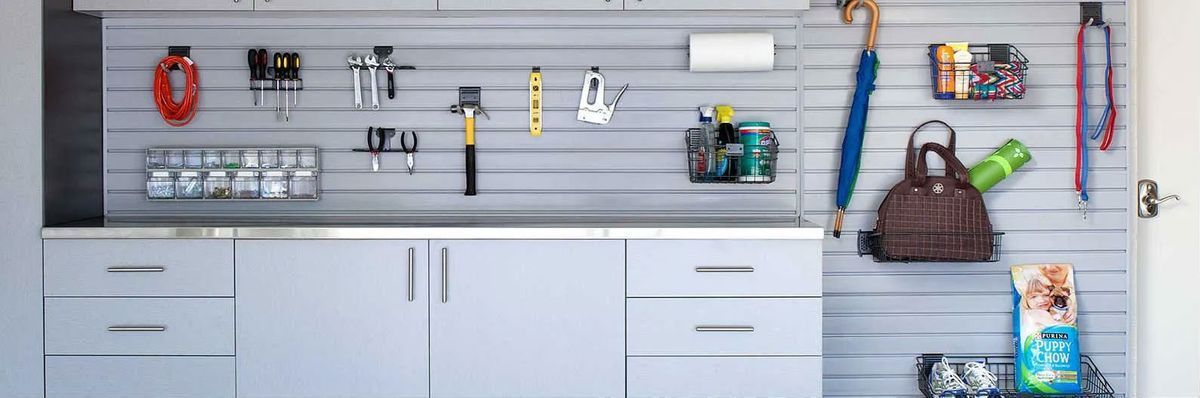 A kitchen with white cabinets , drawers , a sink , and a wall with a bunch of hooks on it.