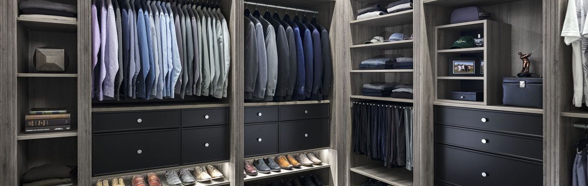 A well-organized walk-in closet with dark-colored drawers and shelves, filled with clothes and shoes.