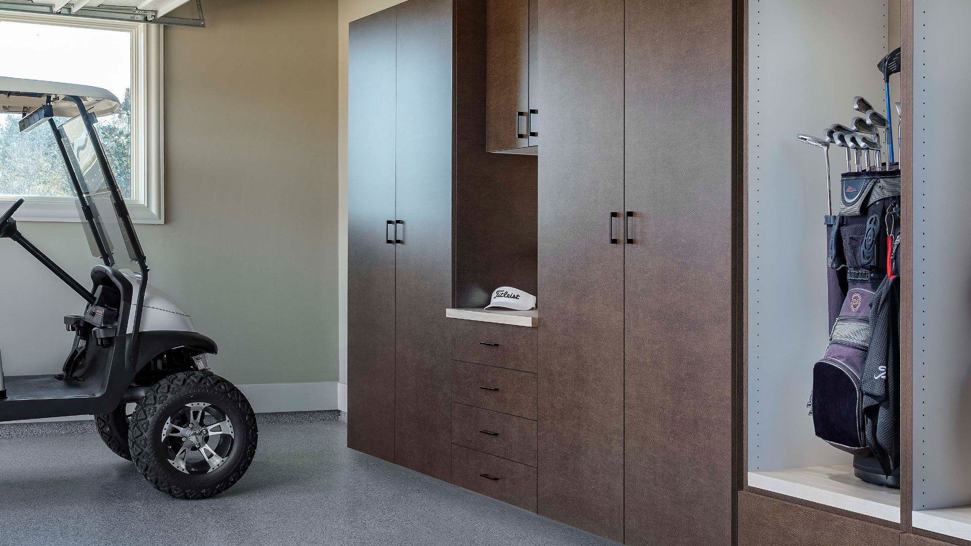 A golf cart is parked in a garage next to a golf bag.