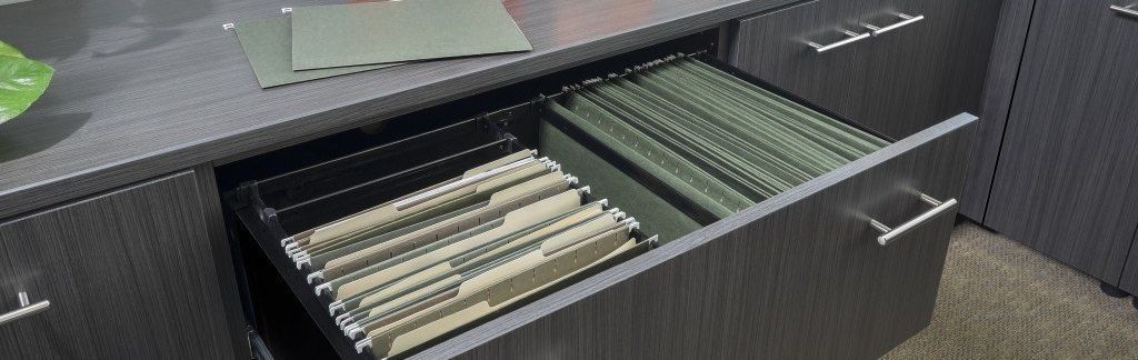 A drawer filled with folders is open on a desk.