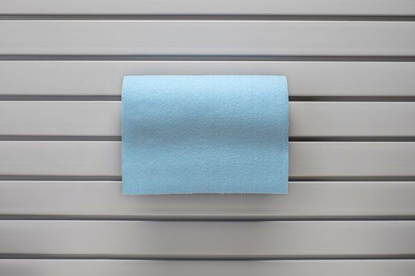 A roll of blue paper towels is hanging on a rack on a wall.