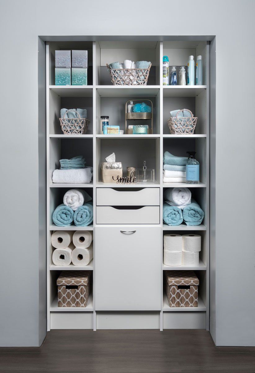 A linen closet filled with towels , toilet paper , baskets , and a trash can.