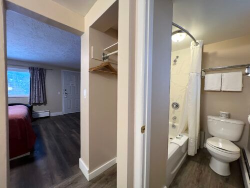 A bathroom in a hotel room with a toilet , bathtub and shower.