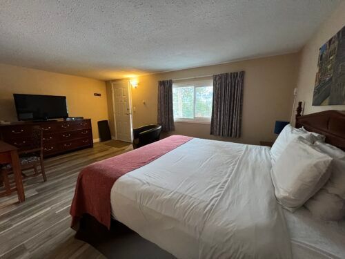 A hotel room with a king size bed and a flat screen tv.