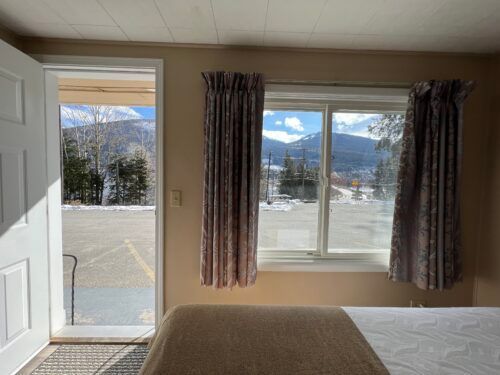 A bedroom with a bed and a window with a view of the mountains.