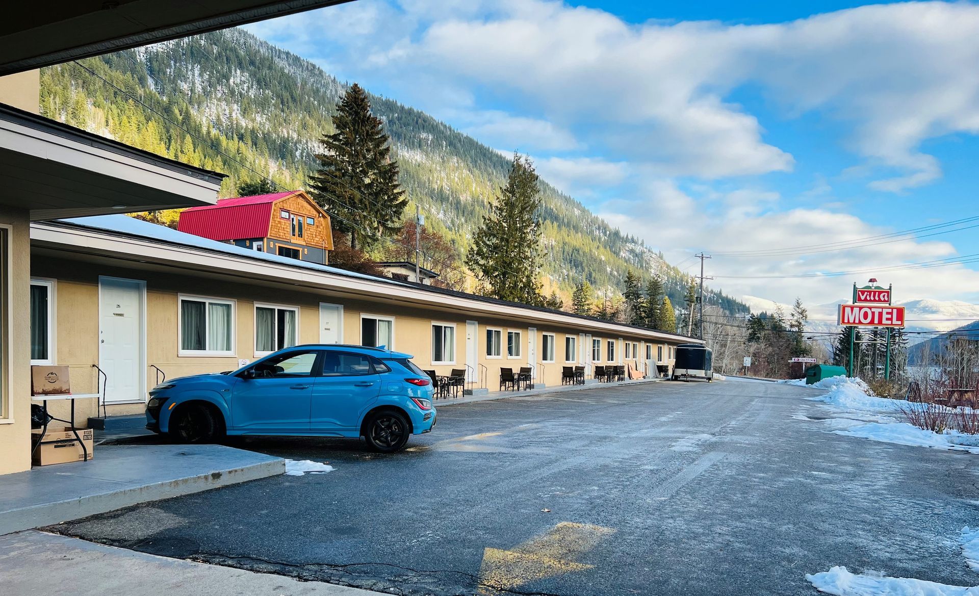 A large building with cars parked in front of it and mountains in the background.