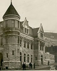 A black and white photo of a large brick building with a tower on top.