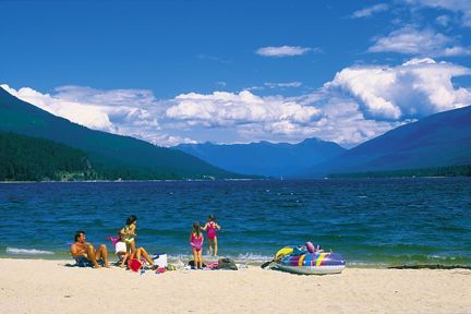 A group of people are playing on a beach with mountains in the background.