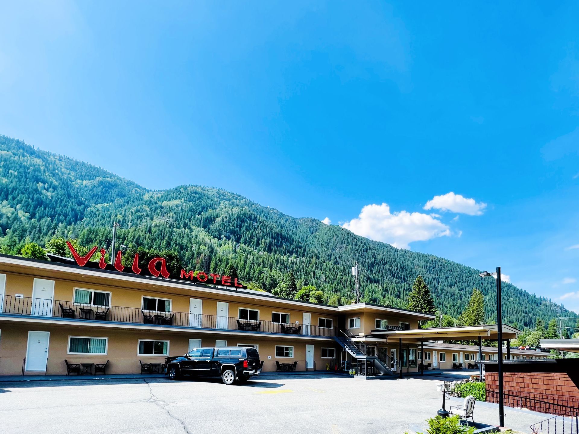 A motel with mountains in the background and a car parked in front of it.