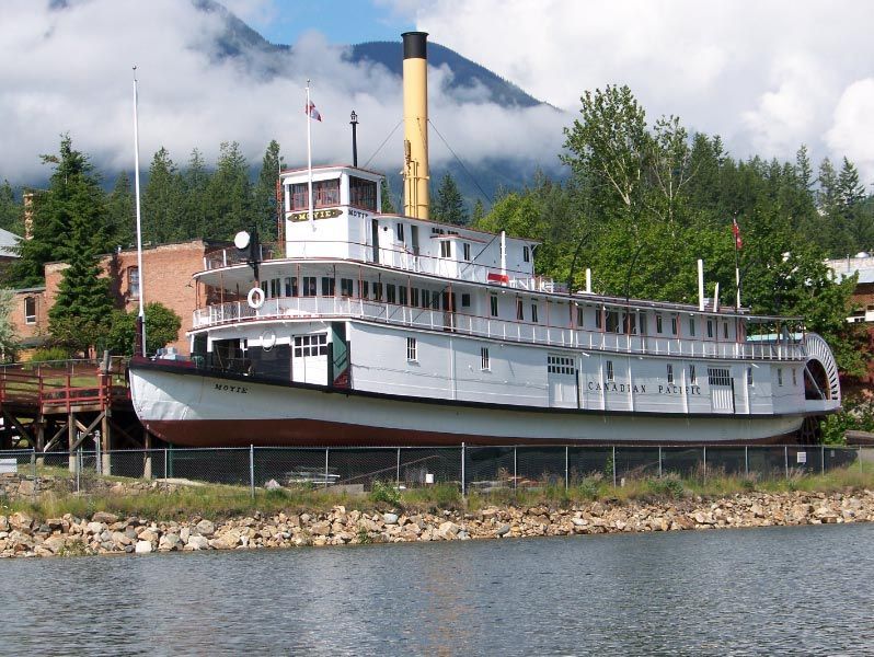 A large boat sits in the water with mountains in the background