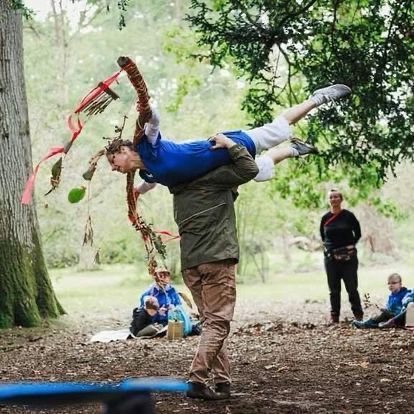 A man is carrying a woman on his shoulders in a park.