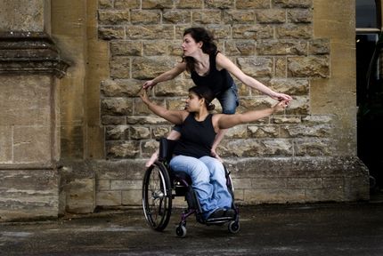 A woman in a wheelchair is being lifted by another woman