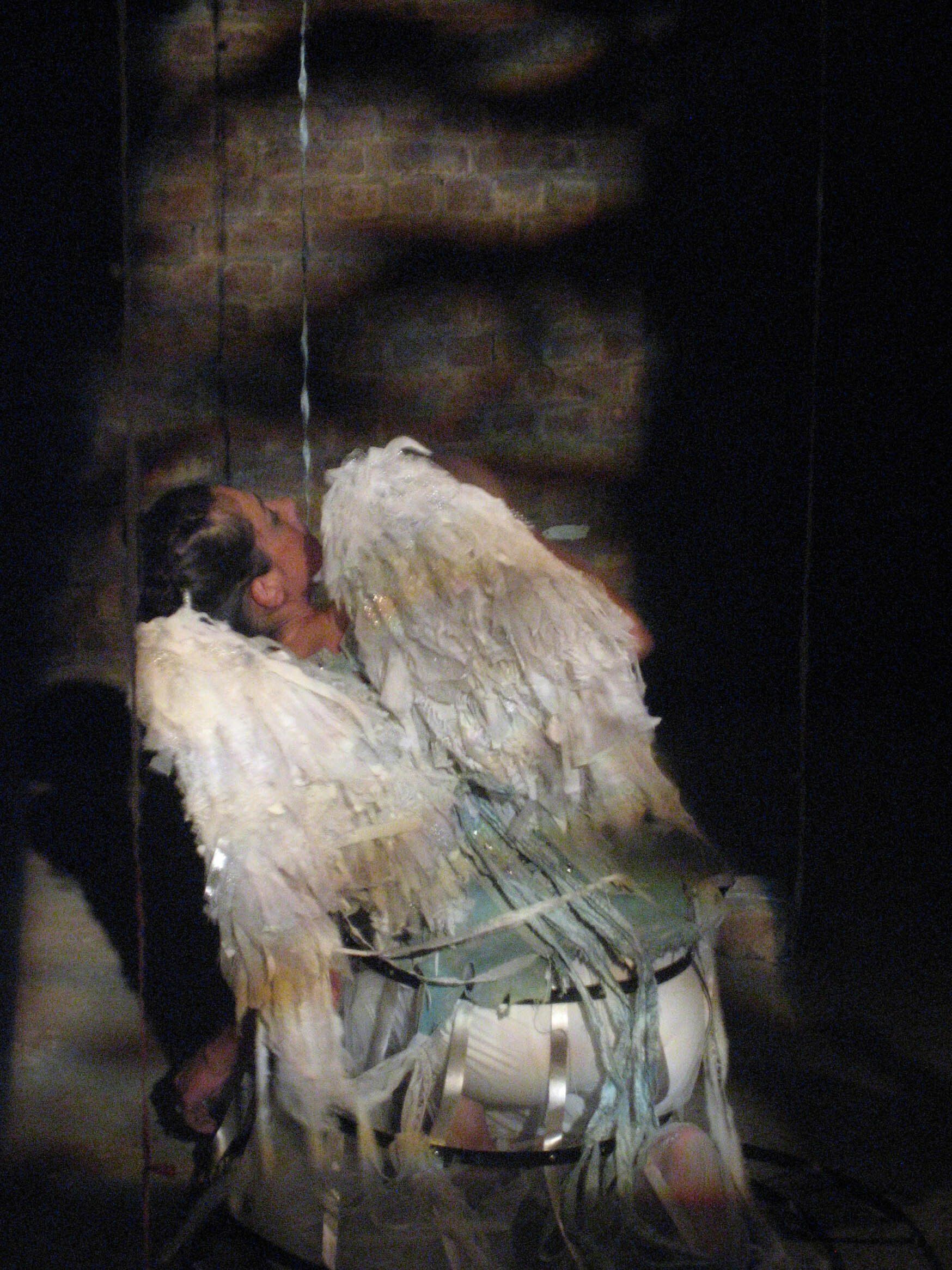 A person with angel wings is sitting on a drum